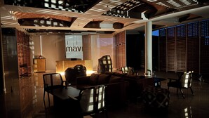 A modern lounge area with seating, a reception desk, and a large illuminated sign.