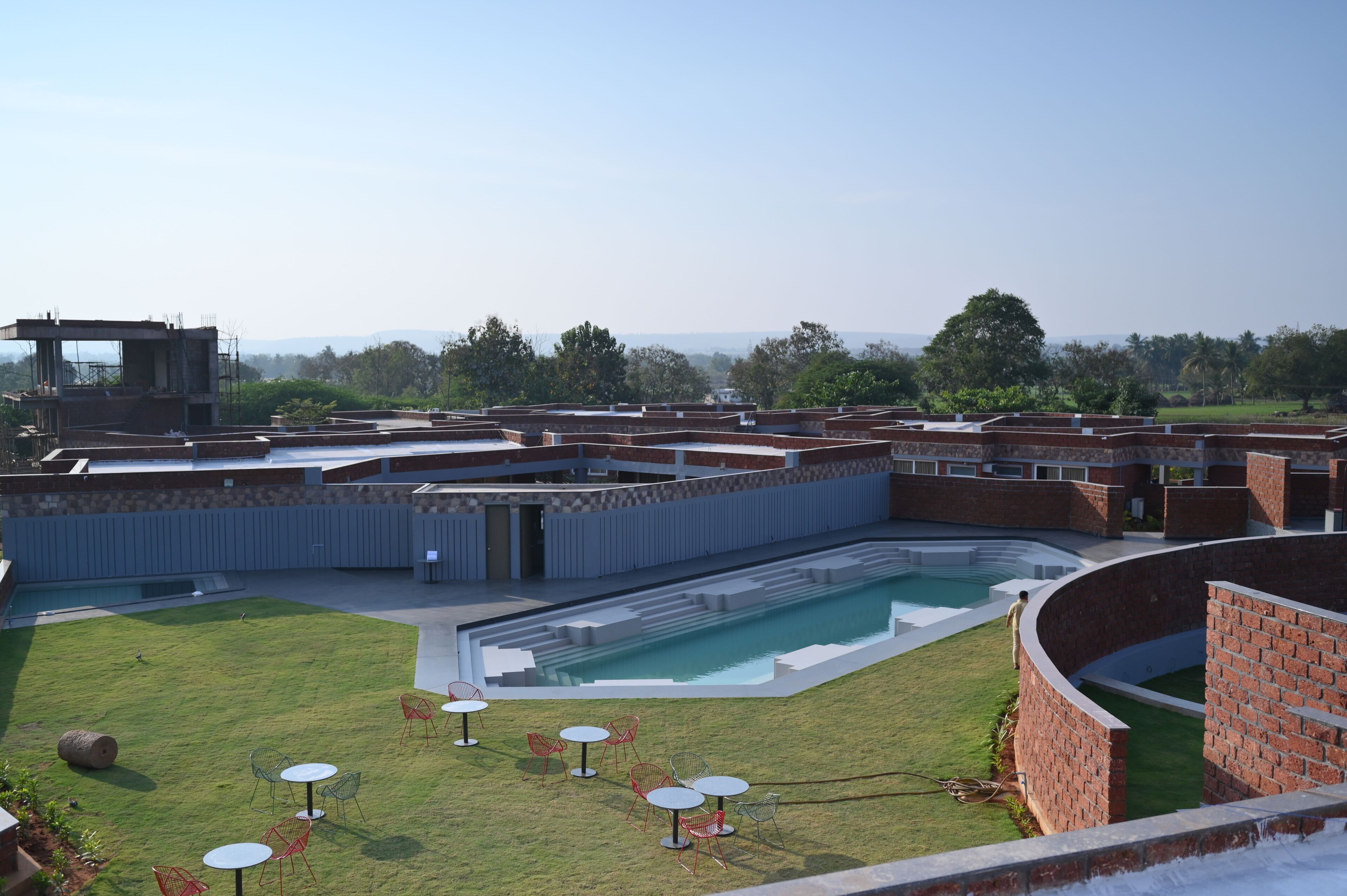 Un área de piscina con vistas despejadas del paisaje circundante, incluyendo un edificio de techo plano y una estructura de ladrillo.