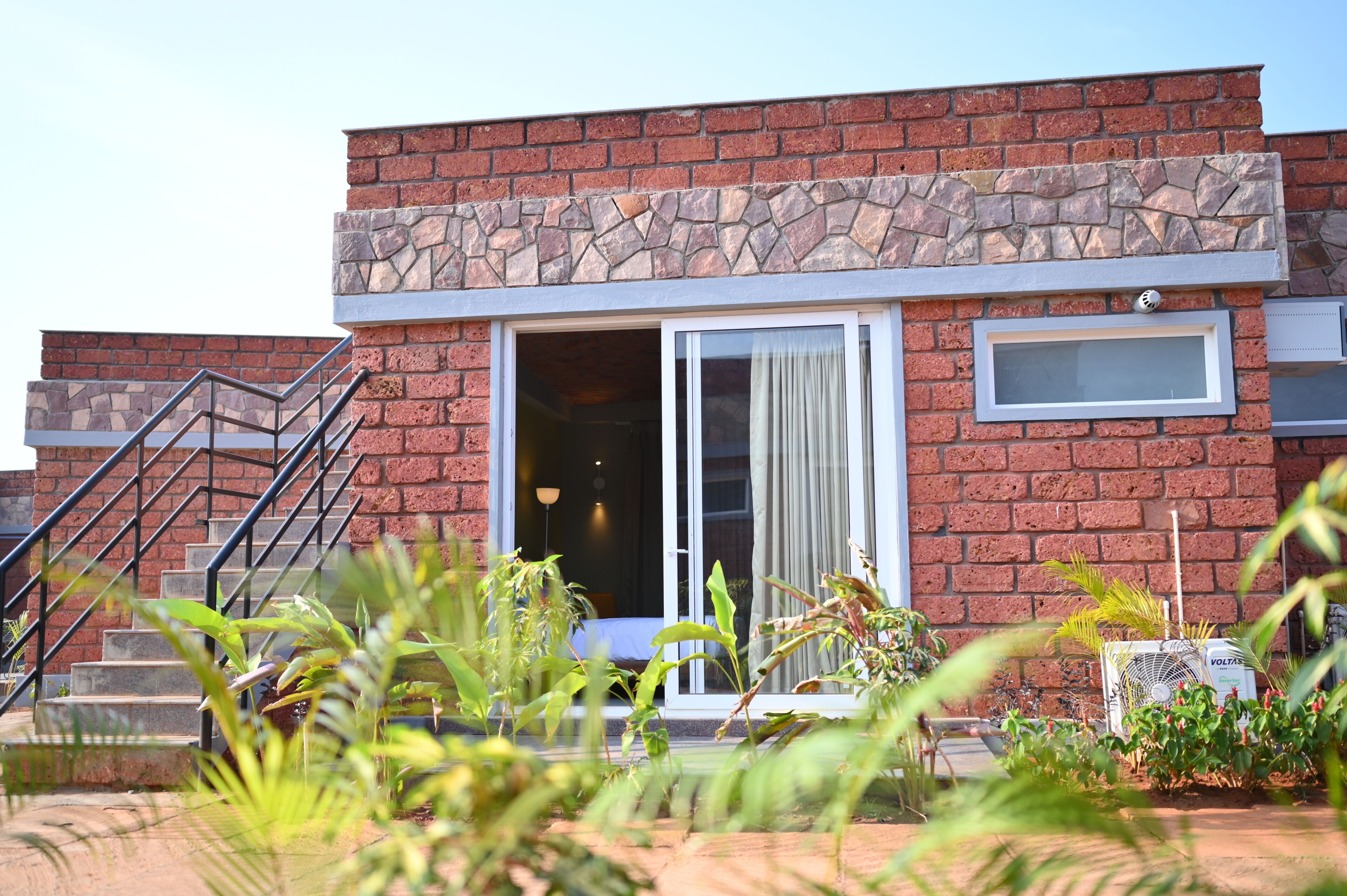 A building with a stone facade, a staircase, and a door leading to an interior space.