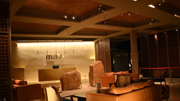 A modern lobby with a reception desk, seating area, and a large rock sculpture.