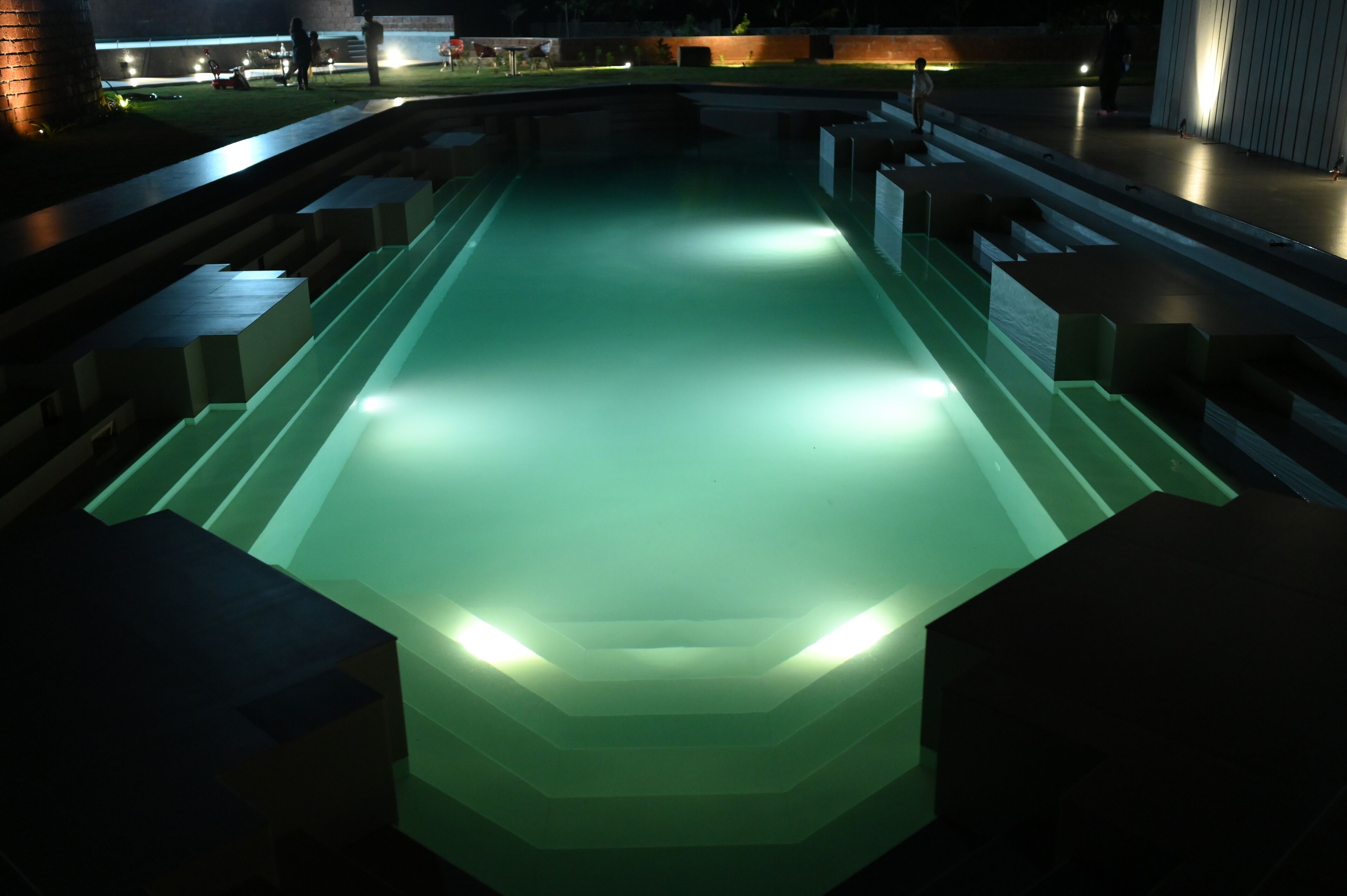 A pool with a geometric design and steps leading into it.