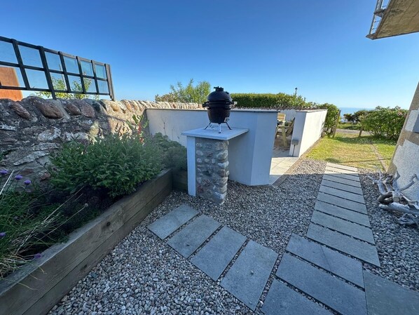 A patio area with a barbecue grill, stone steps, and a view of the sea. - The Old Coastguard Station, Helmsdale (Helmsdale)