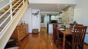 Een moderne keuken met een centraal eiland, houten vloer en een eethoek met een tafel gedekt voor vier personen.