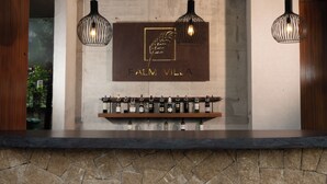 A reception area with a stone wall, a wooden counter, and three hanging pendant lights. - Palm Villa (Mang Yang)
