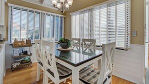 Un coin repas avec une table en verre, des chaises blanches et un lustre.