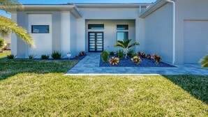 Une maison moderne à deux étages, dotée d’une entrée à l’avant, d’un garage et d’une pelouse bien entretenue.