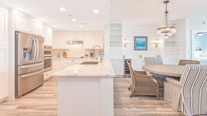 Une cuisine moderne avec des meubles blancs, des appareils en acier inoxydable et un îlot en marbre.