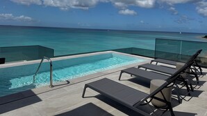 A poolside area with lounge chairs and a view of the ocean. - Luxurious Oceanfront Condo with Rooftop Pool on Brighton Beach– Sleeps 4 (Bridgetown)