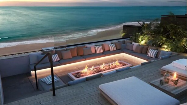 A deck with a fire pit, outdoor seating, and a view of the ocean. - Luxurious Oceanfront Condo with Rooftop Pool on Brighton Beach– Sleeps 4 (Bridgetown)