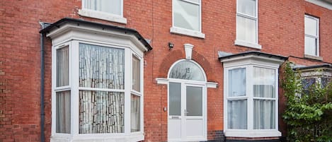 A red brick house with a bay window and a front door.
