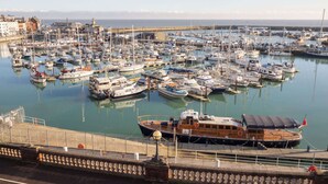 A marina with numerous boats docked, a large ship in the foreground, and buildings in the background. - Host & Stay | Harbour Rest (Ramsgate)