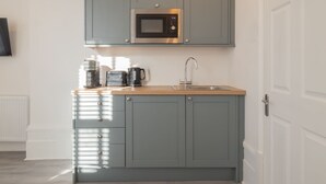 A compact kitchen with grey cabinets, a stainless steel microwave, a coffee maker, and a sink. - Host & Stay | Harbour Rest (Ramsgate)