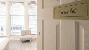 A hotel room with a bed, a chair, a window with blinds, and a sign that reads "Harbour Rest". - Host & Stay | Harbour Rest (Ramsgate)