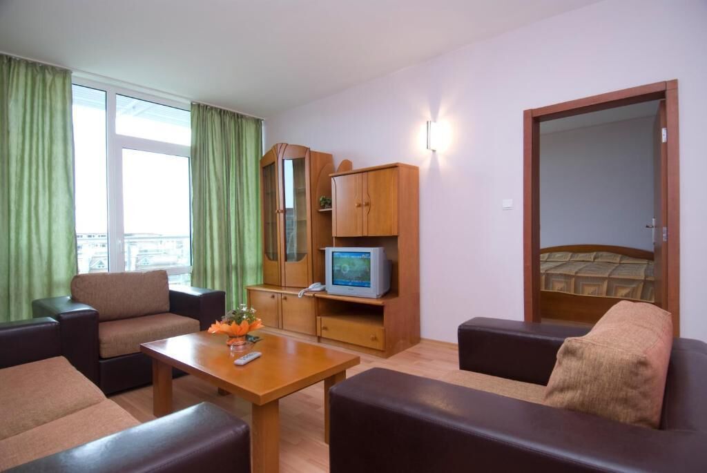 A furnished living room with a sofa, armchairs, a coffee table, a television, and a cabinet.