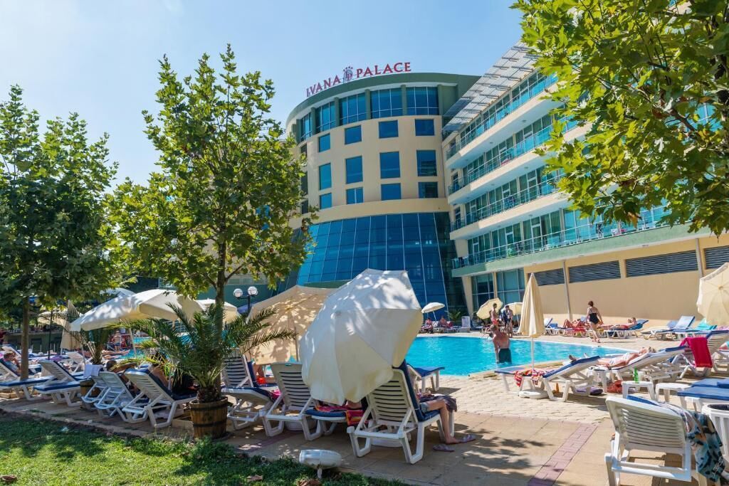 A hotel with a pool area, lounge chairs, and umbrellas.