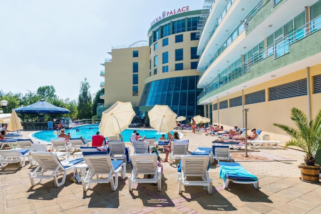 A hotel with a pool area, lounge chairs, and umbrellas.