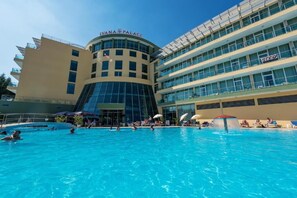 Un hotel con piscina, un edificio moderno con fachada curva y varios balcones.
