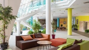 A spacious indoor area with multiple seating arrangements, a staircase, and potted plants. - Hotel Ivana Palace (Sunny Beach)