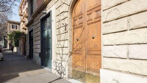 A street view with a building featuring large wooden doors and a stone facade.