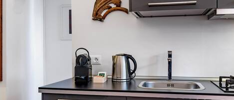 Una cucina moderna con lavello in acciaio inossidabile, bollitore e macchina da caffè sul piano di lavoro.