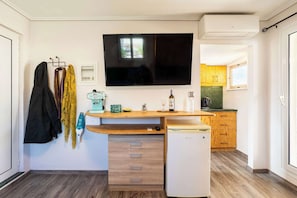 A compact kitchen with a built-in dishwasher, a flat-screen TV, and wooden cabinets.