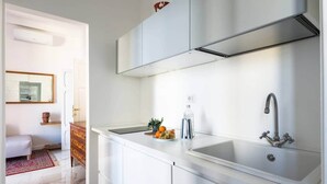 A modern kitchen with white cabinetry, a stainless steel sink, and a built-in oven. - Glorioso Marble | Trastevere ArtDesignApartments (Roma)