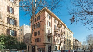 A row of multi-story buildings with balconies, parked cars, and a clear blue sky. - Glorioso Marble | Trastevere ArtDesignApartments (Roma)