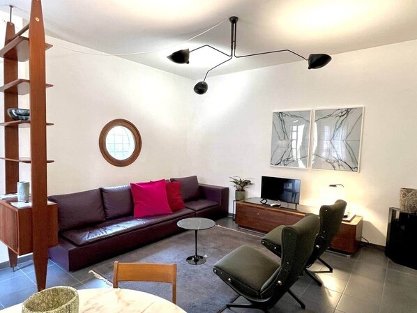 A modern living room with a sofa, a coffee table, a TV, and a bookshelf.