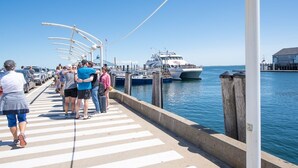 Eine Pier mit Menschen, die darauf entlanggehen, und einem Boot, das am Ende festgemacht ist.