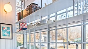 Eine moderne Küche mit großem Fenster, Spüle aus Edelstahl und Holzschränken.