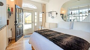 Ein Schlafzimmer mit einem großen Bett, einem Spiegel, einem Fenster und einer Tür mit einem Schild.
