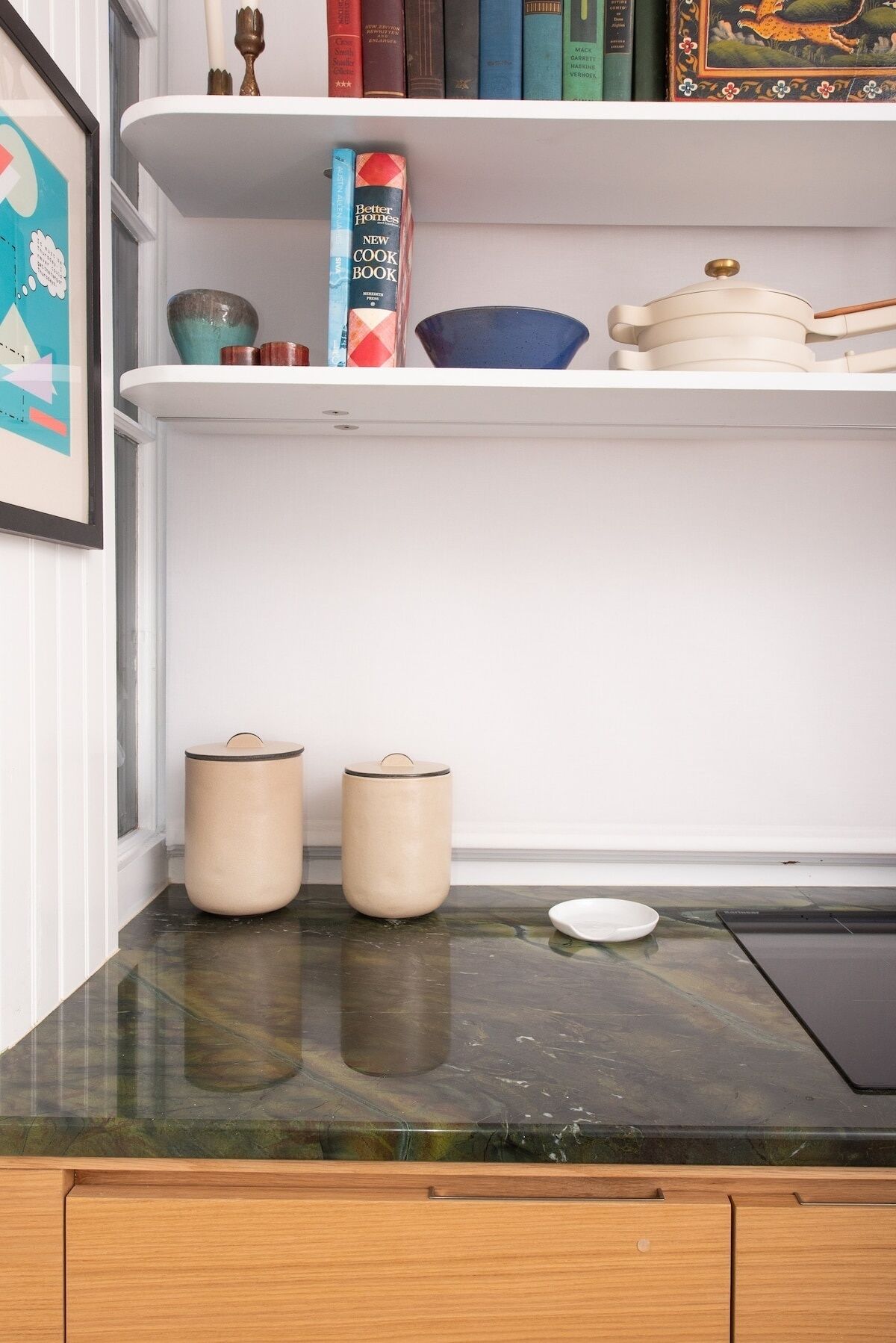 A kitchen counter with a marble top, two beige containers, a white plate, and a tablet.