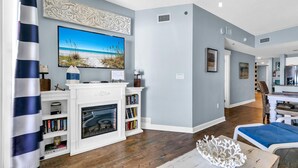 A living room with a fireplace, bookshelves, a television, and a dining area with a table and chairs.