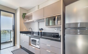 Cozinha moderna com forno embutido, geladeira de aço inoxidável e uma janela ampla com vista panorâmica.