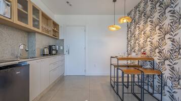 Una cocina moderna equipada con lavavajillas, cafetera y zona de comedor con mesa y sillas.