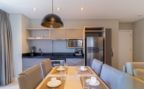 Une cuisine moderne avec un coin repas, comprenant une table dressée pour deux personnes, avec assiettes, verres et couverts.
