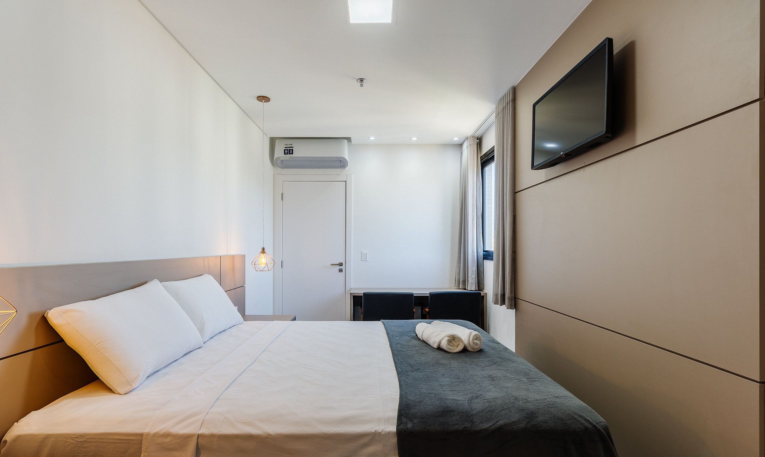 Une chambre d’hôtel équipée d’un lit, d’un bureau, d’une télévision et d’un climatiseur.