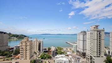 Un paysage urbain côtier avec de hauts immeubles, un ciel dégagé et une mer calme.