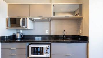 Una cocina moderna con microondas integrado, cafetera y lavabo.