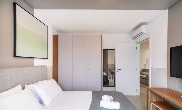 Quarto de hotel moderno com cama, guarda-roupa, espelho e televisão.