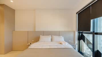Un dormitorio moderno con una cama grande, una mesita de noche y una ventana.