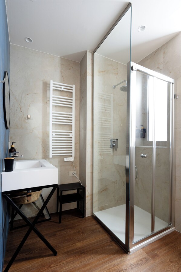 A modern bathroom with a glass-enclosed shower, a white sink, and a towel rack.