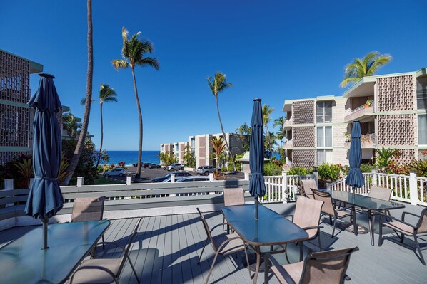 Eine Terrasse mit Sitzgelegenheiten, Palmen und Blick auf das Meer.