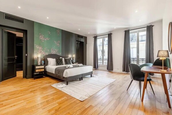 Relax in a stylish room with a large bed, green accent wall, and a dining area by the window.