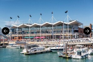 A waterfront building with multiple levels, a covered outdoor area, and boats docked in the water. - Irtaza charming suits 

 (Waterlooville)