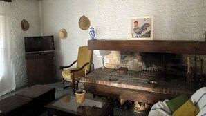 A cozy living room with a fireplace, a television, and a comfortable chair. - Gîte du Puy des Gardes (Meymac)