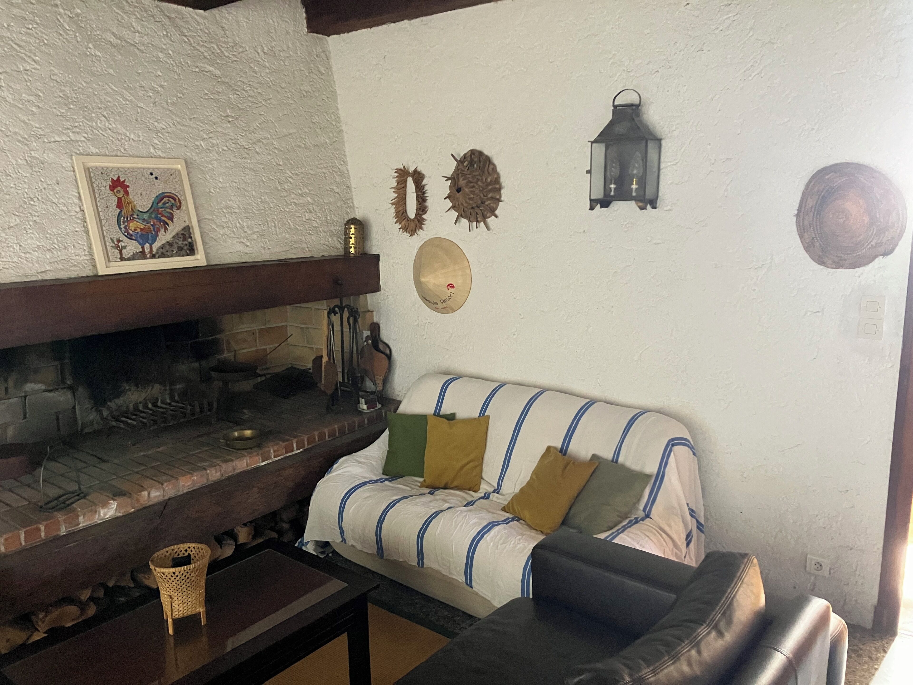 A cozy living room with a fireplace, a sofa, and various wall decorations.