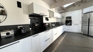 A modern kitchen with white cabinets, black countertops, and stainless steel appliances. - House RIVAGE       . (Sainte-Marie-de-Ré)