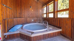 Una cabaña de madera con un jacuzzi, una toalla y un ventanal.