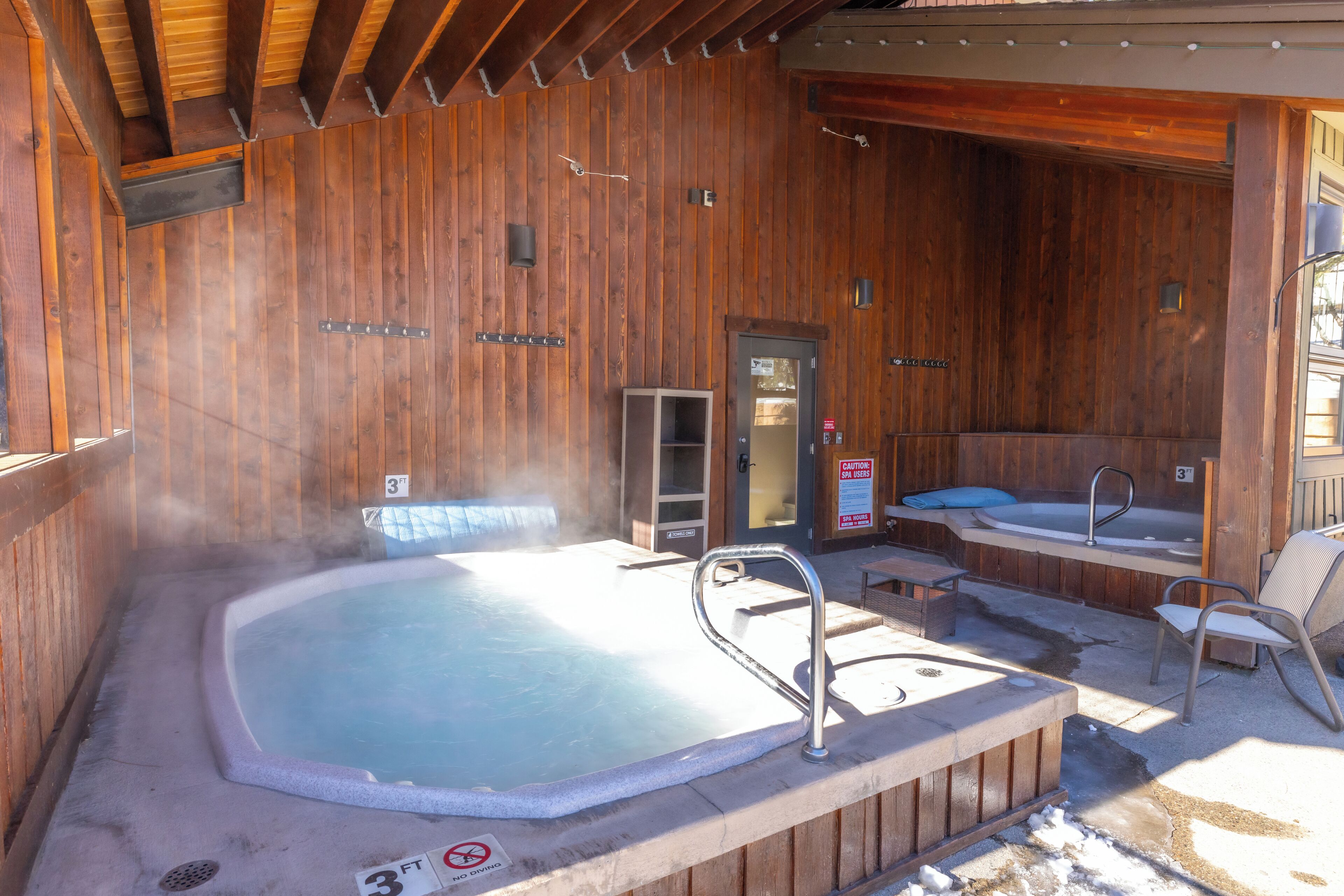 Ein Spa-Bereich aus Holz mit Whirlpool, Dusche und einer Sitzecke.
